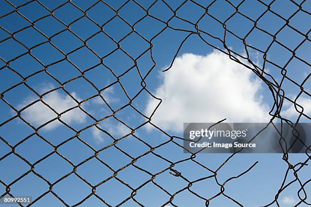 cloud through a broken fence - chainlink fence stock pictures, royalty-free photos & images