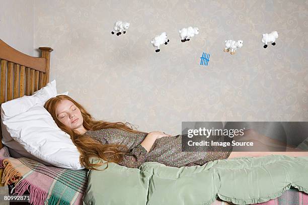 a young woman counting sheep - sleeping sheep stock pictures, royalty-free photos & images