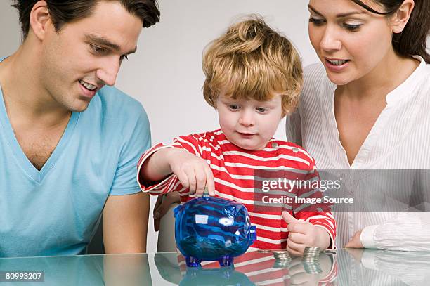 boy and parents with piggy bank - taschengeld kind stock-fotos und bilder