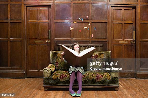 a teenage girl reading a large book - the legend of merlin and arthur stockfoto's en -beelden