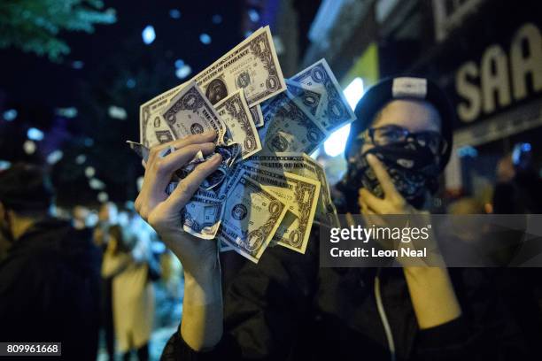 Woman holds up a handful of fake US currency during the ÒWelcome to HellÓ anti-G20 protest march on July 7, 2017 in Hamburg, Germany. Leaders of the...