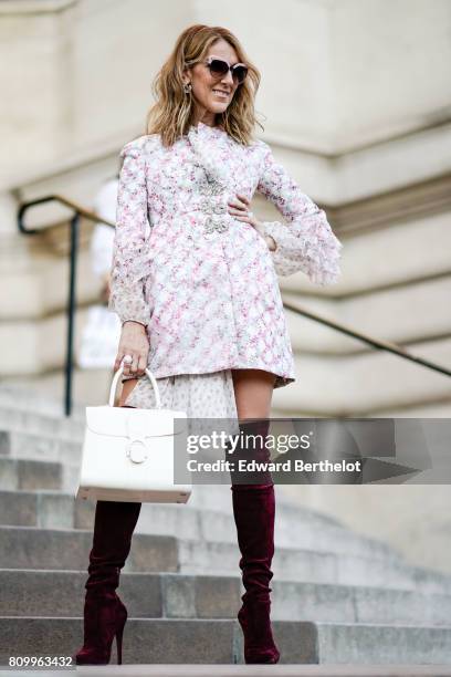 Celine Dion wears sunglasses, a dress with embroidered features and lace, a white bag, and purple thigh high velvet boots, outside the Giambattista...