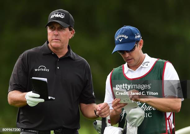 Phil Mickelson converses with his brother and caddie Tim on the 11th tee during round one of The Greenbrier Classic held at the Old White TPC on July...