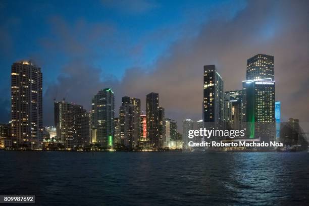 City urban skyline at night from the Biscayne Bay. Tall buildings with lights on, point of view from a tourist boat.