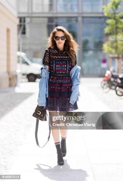 Alexandra Lapp wearing a mini lace dress in navy blue and heady red from Self-Portrait, a Roger Viv mini bag crafted in suede with waterjet cut...