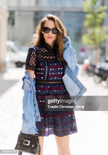 Alexandra Lapp wearing a mini lace dress in navy blue and heady red from Self-Portrait, a Roger Viv mini bag crafted in suede with waterjet cut...