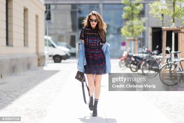 Alexandra Lapp wearing a mini lace dress in navy blue and heady red from Self-Portrait, a Roger Viv mini bag crafted in suede with waterjet cut...