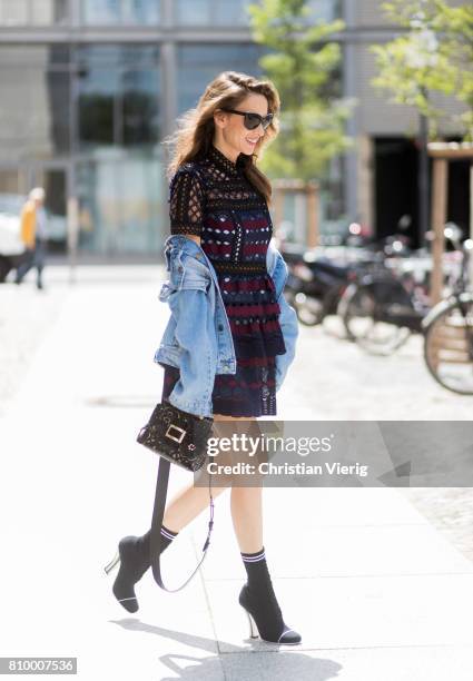 Alexandra Lapp wearing a mini lace dress in navy blue and heady red from Self-Portrait, a Roger Viv mini bag crafted in suede with waterjet cut...