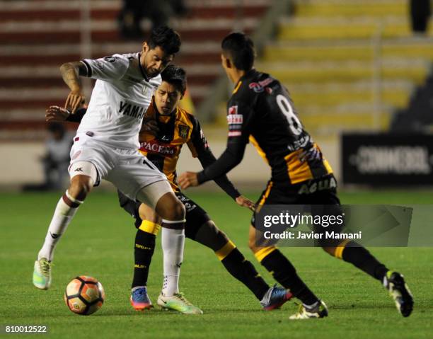 Diego Wayar and Diego Bejarano of The Strongest fight for the ball with Roman Martinez of Lanus during a first leg match between The Strongest and...