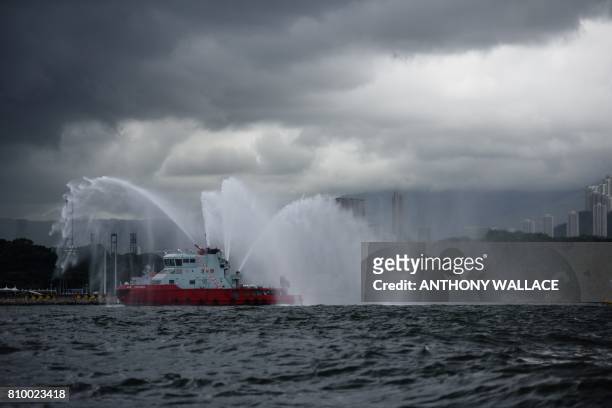 Fire boat sprays a water salute as it welcomes China's sole aircraft carrier, the Liaoning, upon its arrival in Hong Kong waters on July 7 less than...