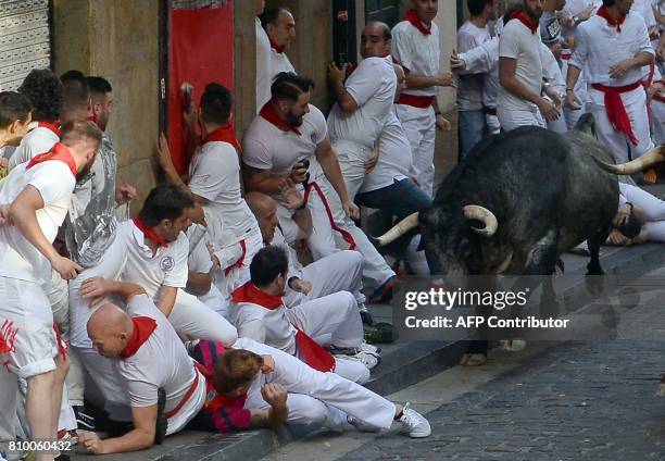 Cebada Gago fighting bull looks at participants as it runs past them on the first day of the San Fermin bull run festival in Pamplona, northern Spain...