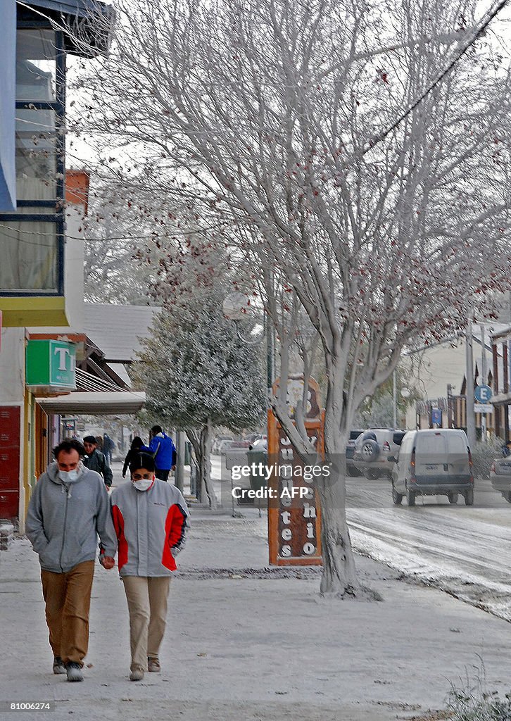 People walk in a street covered with ash