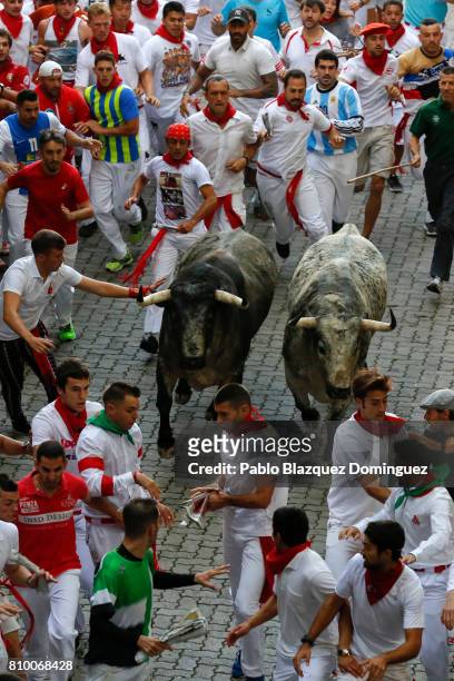 Revellers run with Cebada Gago's fighting bulls entering the bullring during the second day of the San Fermin Running of the Bulls festival on July...