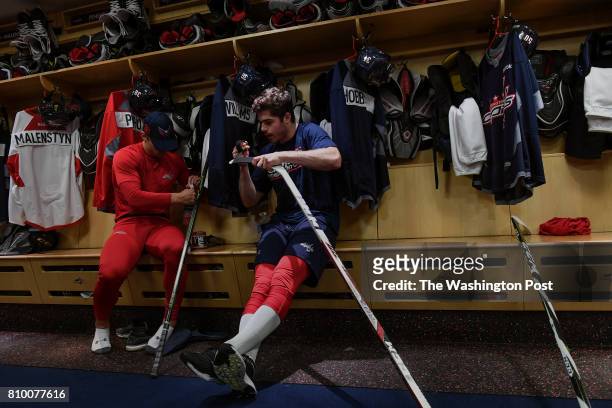 Washington Capitals defensive prospect Connor Hobbs, right, and Colby Williams, left, re-tape their sticks before practice during the Washington...