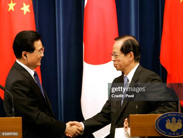 Chinese President Hu Jintao and Japanese Prime Minister Yasuo Fukuda shake hands during a joint press conference at Fukuda's official residence on...