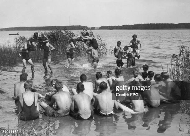 Members of the German Hitler Youth organization enjoy piggy-back fights at the edge of the Ruppiner See near Neuruppin, Germany, during a summer...
