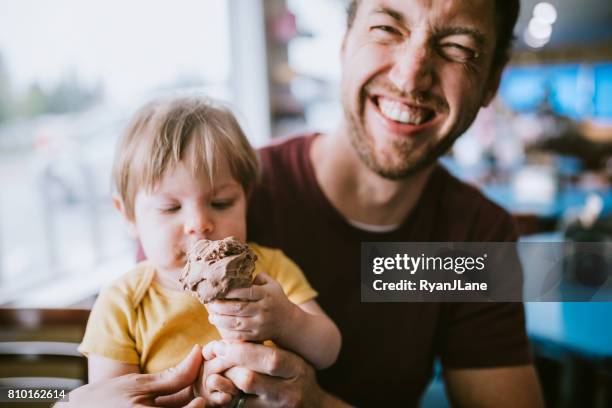 father feeding baby ice cream cone - ice cream parlour stock pictures, royalty-free photos & images