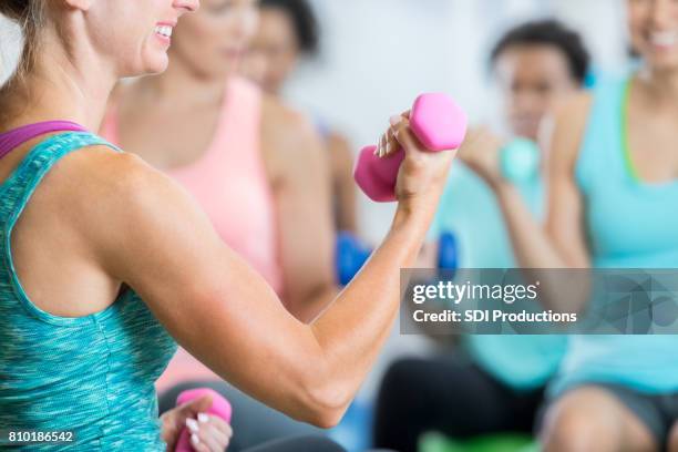 athletic woman uses hand weight in gym - group of people flexing biceps stock pictures, royalty-free photos & images