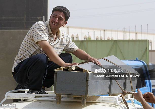 The son of Ali Haten grieves as his father's coffin is tied to the roof of a taxi to be taken to the holy southern city of Najaf for burial, outside...