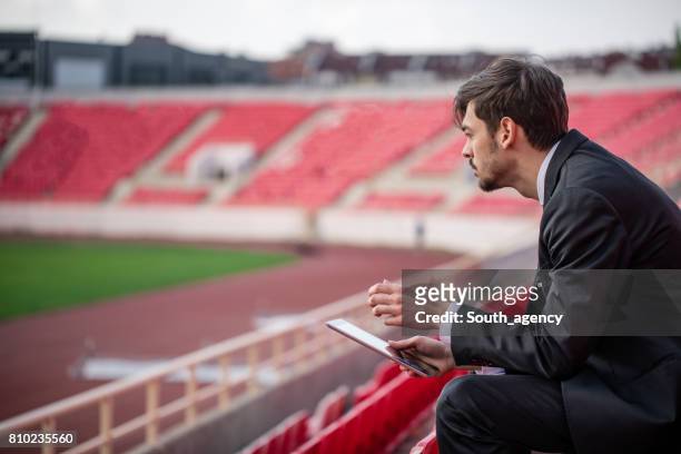 jongeman zit op de tribune van het stadion - cheftrainer stockfoto's en -beelden