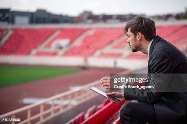 young man sitting on stadium grandstand - sport manager stock pictures, royalty-free photos & images