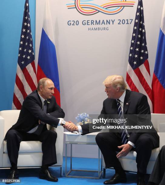 President Donald Trump and Russia's President Vladimir Putin shake hands as they hold a meeting on the sidelines of the G20 Summit in Hamburg,...