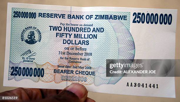 An unidentified man holds the new Zimbabwean Two Hundred and Fifty million dollar banknote issued by the Reserve Bank on May 08, 2008 in Harare,...