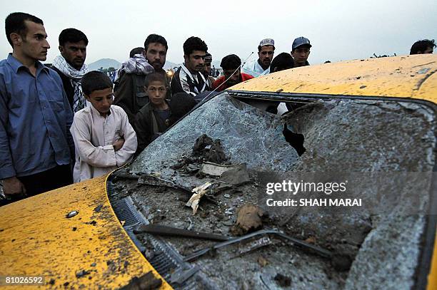 Afghan people gather beside a taxi damaged in a suicide attack in Kabul on May 8, 2008. A suicide car bomb blew up in the Afghan capital Kabul on May...