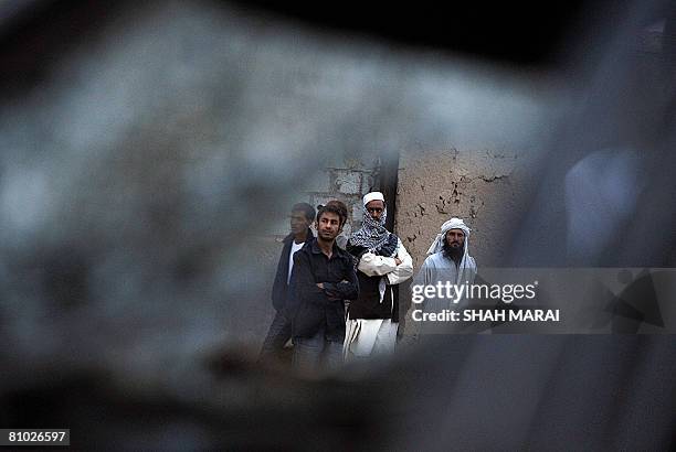 Afghan people gather beside a taxi damaged in a suicide attack in Kabul on May 8, 2008. A suicide car bomb blew up in the Afghan capital Kabul on May...