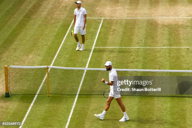 Benoit Paire of France celebrates as Jerzy Janowicz of Poland looks despondent during the Gentlemen's Singles third round match on day five of the...