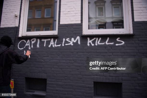 Protester writes on the wall on July 7, 2017 in Hamburg, northern Germany, where leaders of the world's top economies gather for a G20 summit....