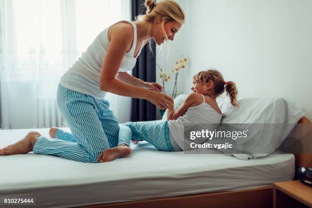 moeder en dochter met plezier in de ochtend in hun bed - kietelen stockfoto's en -beelden