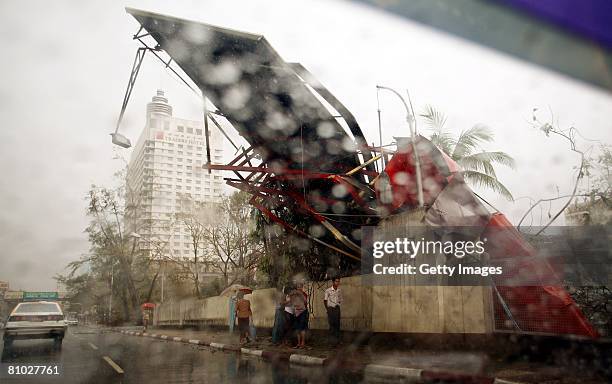 Pedestrians walk beneath a billboard damaged by the effects of Cyclone Nargis on May 8 In Yangon, Myanmar. International Aid Agencies are continuing...