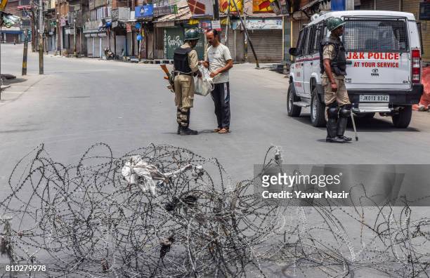 An Indian paramilitary trooper frisks bag of a kashmiri man during a curfew ahead of the first death anniversary of Burhan Wani a young rebel...