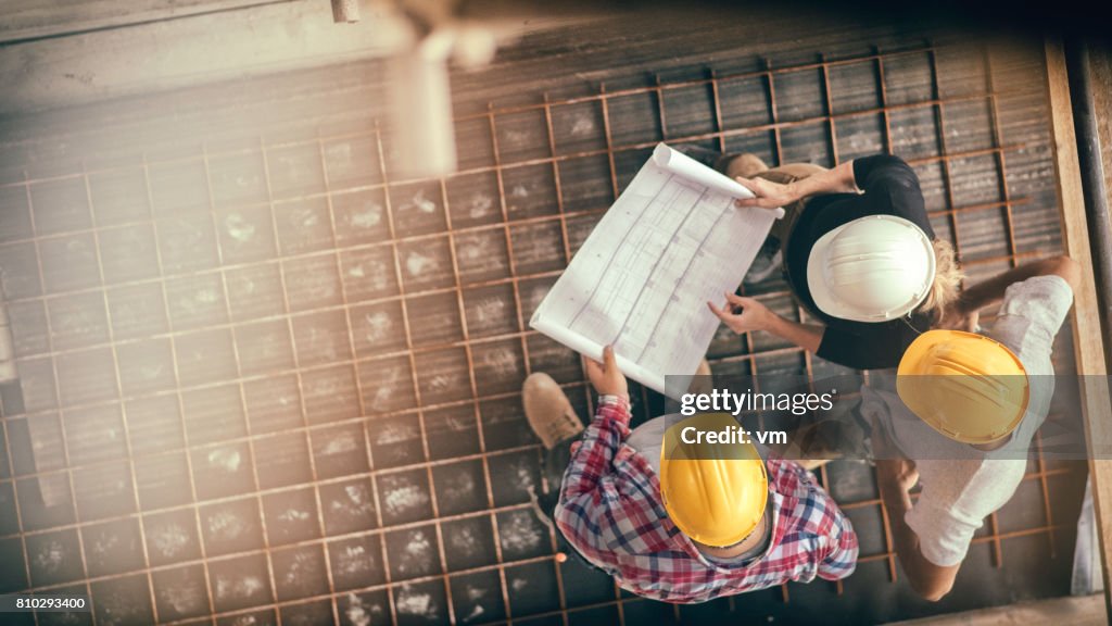 Arquitecto femenino y dos trabajadores de la construccion de una obra