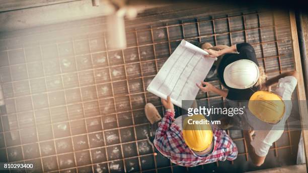 vrouwelijke architect en twee consruction werknemers op een bouwplaats - building contractor stockfoto's en -beelden
