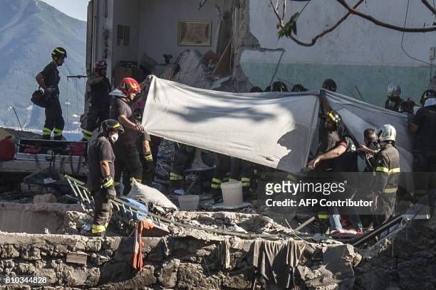 Firefighters block the view with sheets as they extract a body from the debris of a collapsed building, after two floors collapsed in a small...