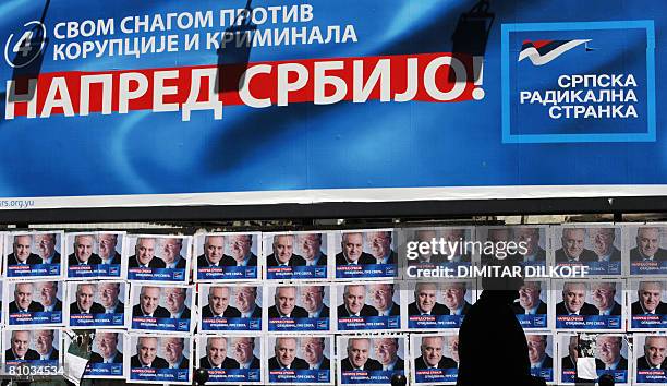 An elderly woman begs money by pre-election posters of Vojislav Seselj, currently on trial in The Hague for war crimes, leader of the hard-line...