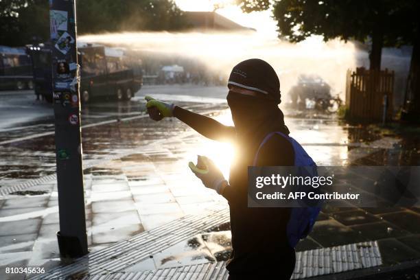 Protester carring stones makes his way to riot police using water cannon against protesters on July 7, 2017 in Hamburg, northern Germany, where...