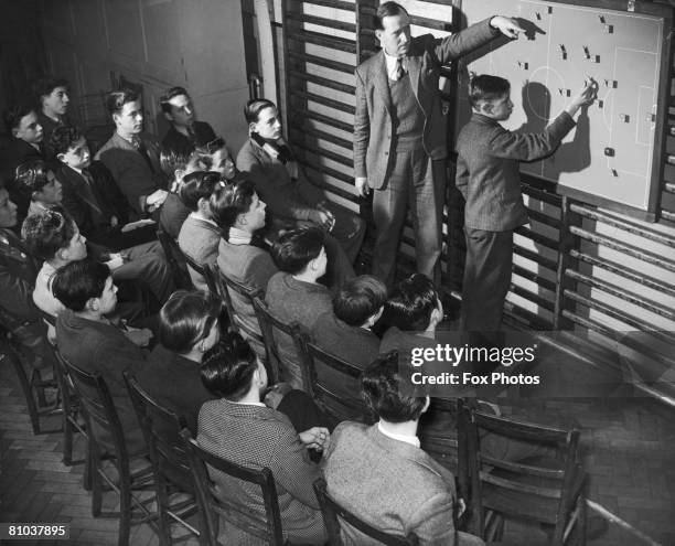 Teacher Eric Ross uses a magnetic football pitch diagram of his own invention to demonstrate tactics to a group of boys from the first and second...