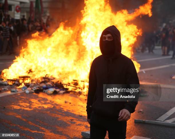 Face covered protester walks by a fire, started by protesters to block a road, during the G20 Summit in Schanzenviertel district of Hamburg, Germany...