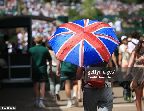 Spectator shelters from the sunshine under a Union Jack umbrella on day five of the 2017 Wimbledon Championships at the All England Lawn and Croquet...