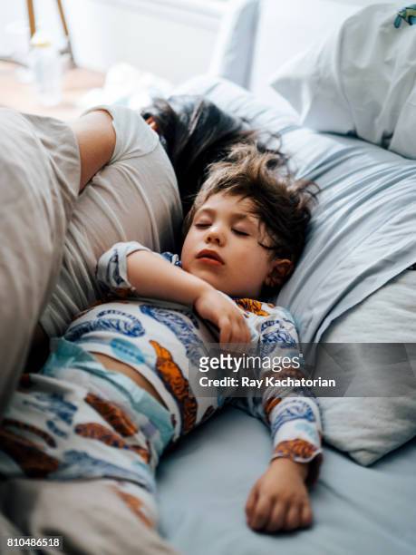 child asleep next to mother - child in bed clothed stock-fotos und bilder