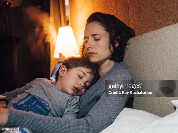 child sleeping in mothers arms - illness fotografías e imágenes de stock