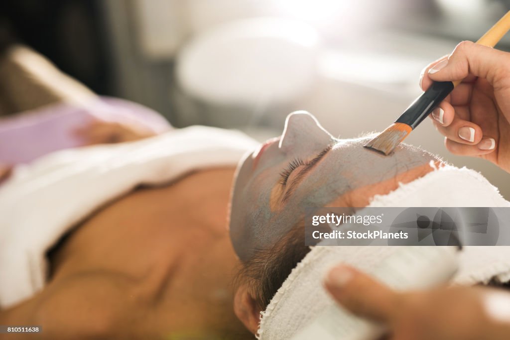 Gros plan de l’application du masque sur le visage de la femme dans un salon de beauté.