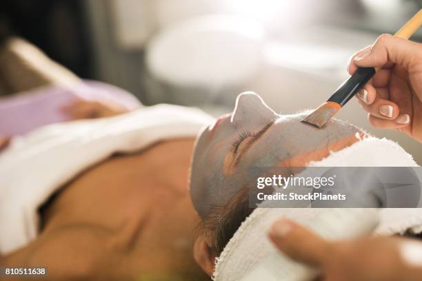 close up of applying facial mask on woman's face in a beauty salon. - beautician stock pictures, royalty-free photos & images