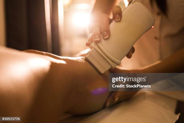 close up of unrecognizable beautician removing her customer's leg hair. - leg waxing stock pictures, royalty-free photos & images