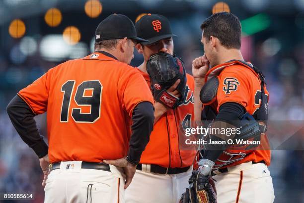 Buster Posey of the San Francisco Giants and pitching coach Dave Righetti talk to Matt Moore on the pitchers mound during the first inning against...