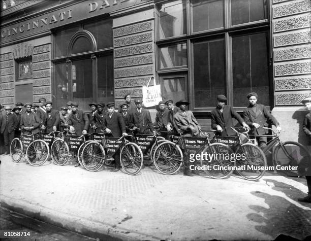Line of newsboys pose with their bicycles as they wait outside the offices of the Cincinnati Daily Star to pick up and deliver the Times-Star...