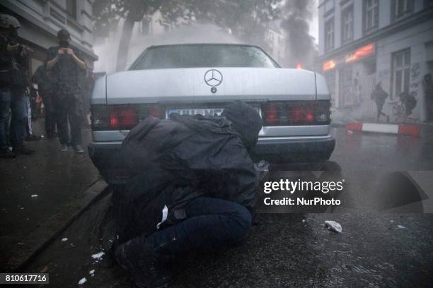 Man hides behind a car during riots in St. Pauli district during G 20 summit in Hamburg on July 8, 2017 . Authorities are braced for large-scale and...